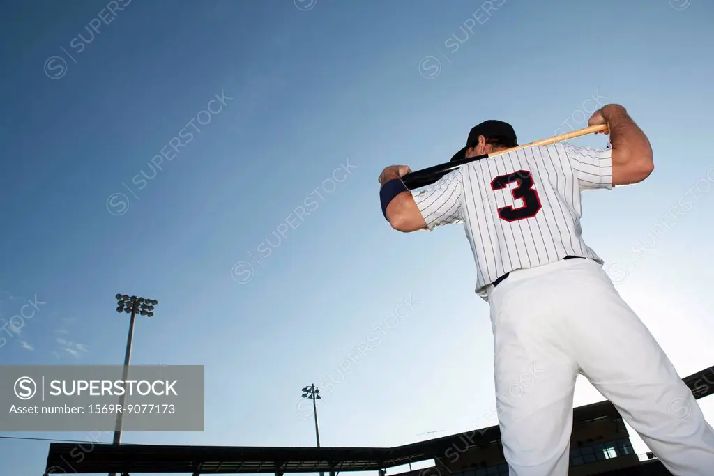 Baseball player holding bat, rear view