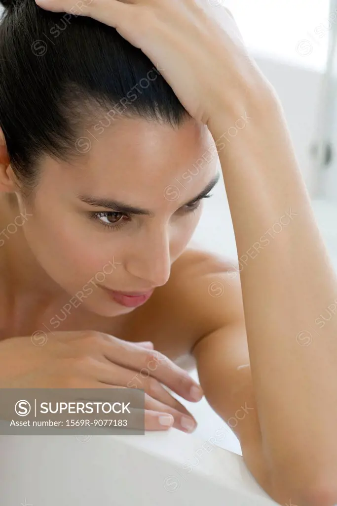 Woman in bath, looking away in thought