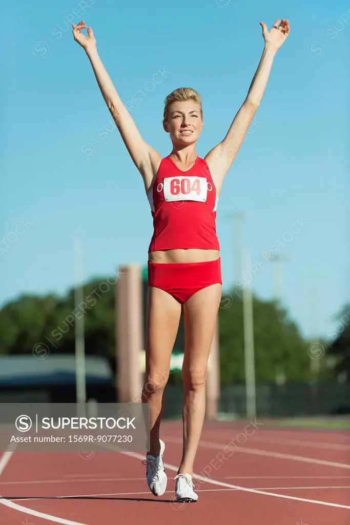 Young woman runner completing race with arms raised
