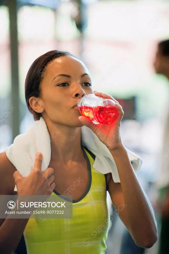 Young woman drinking sports drink after exercising