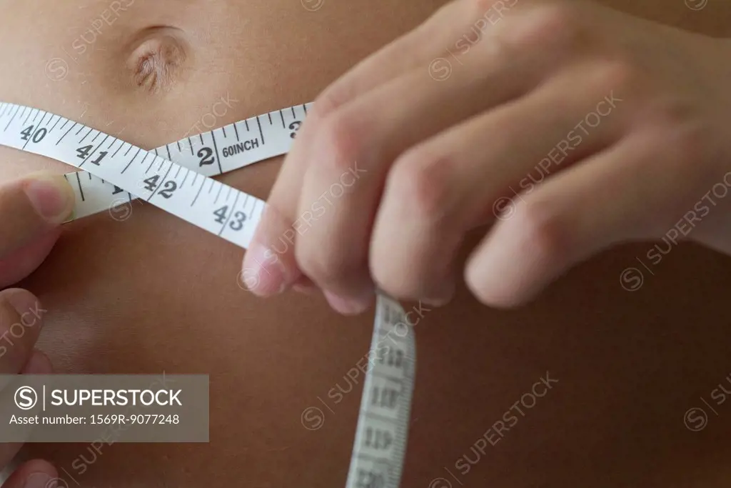 Woman measuring stomach, cropped