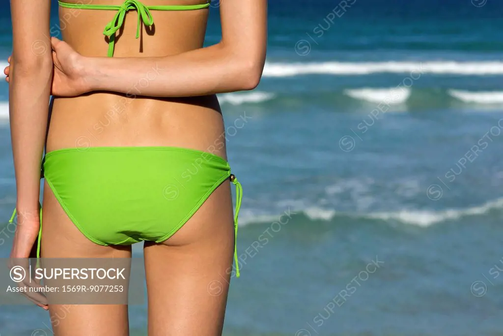 Woman in bikini standing by sea