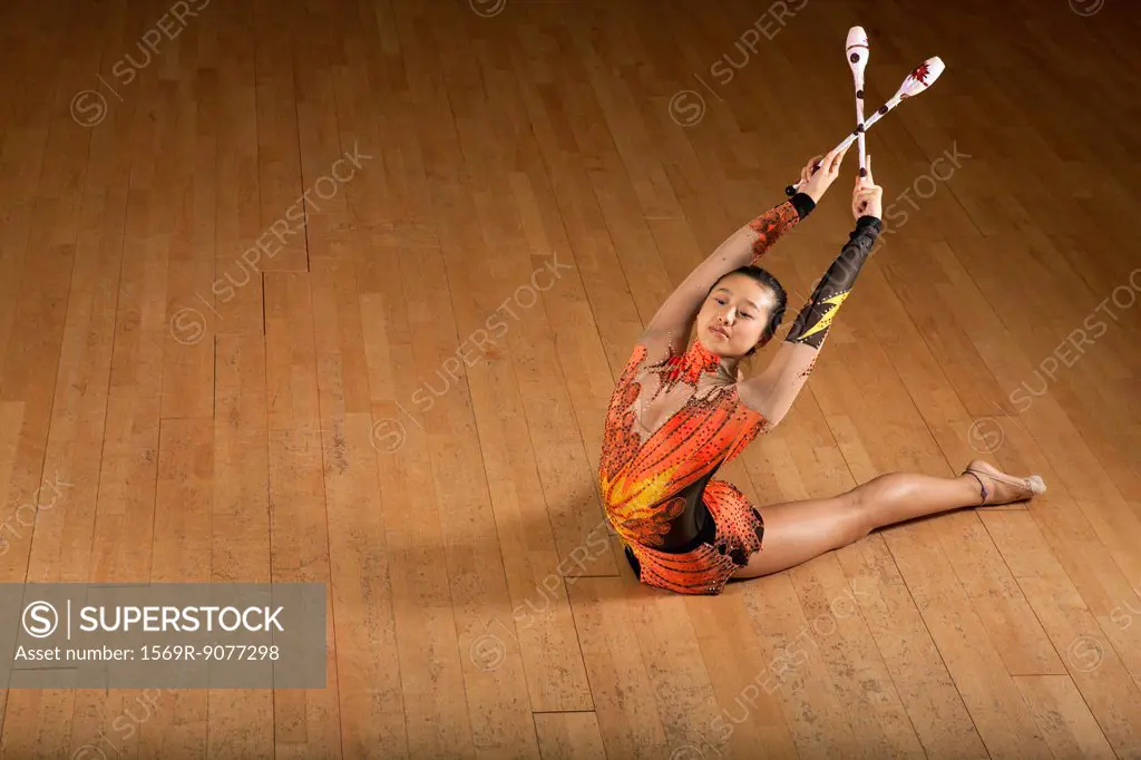 Gymnast bending backwards, holding clubs