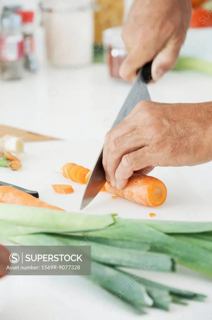 Man slicing fresh vegetables, cropped