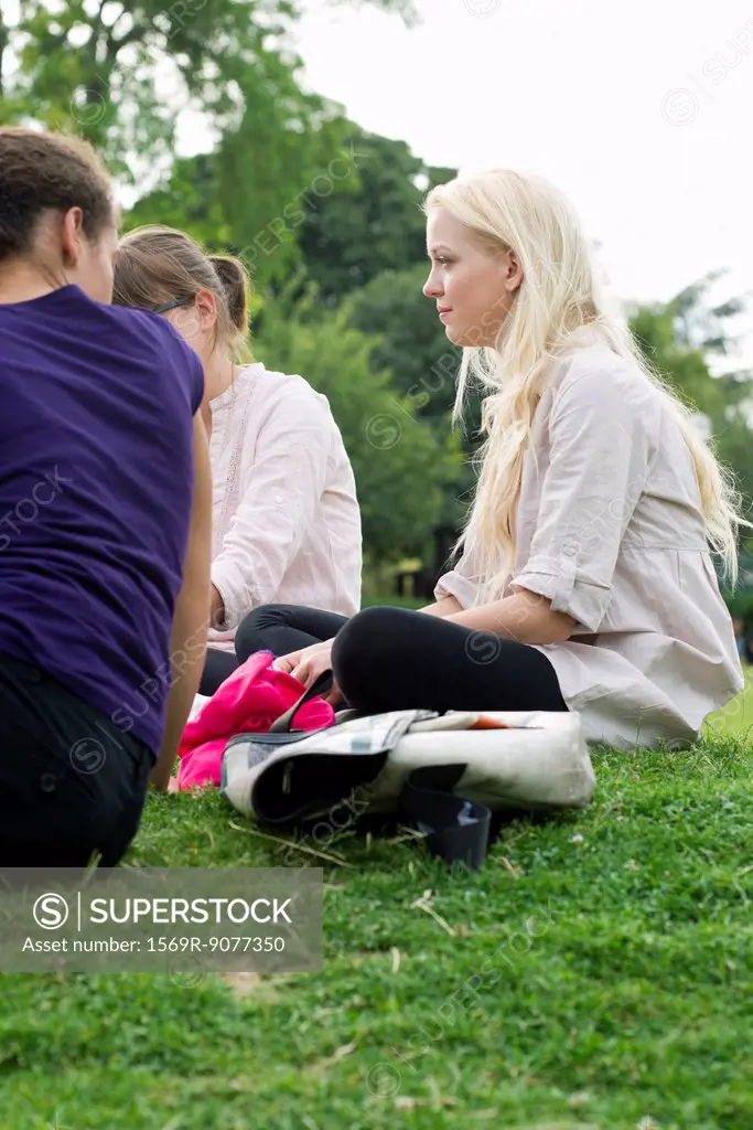 Young woman sitting on grass with friends