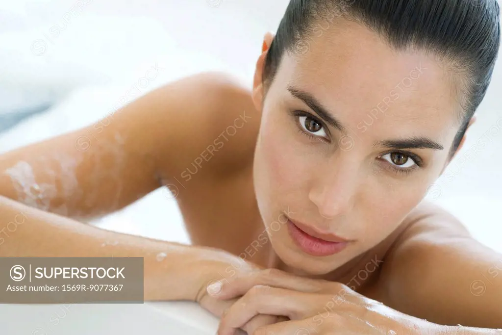 Woman soaking in bath, leaning against edge of bathtub