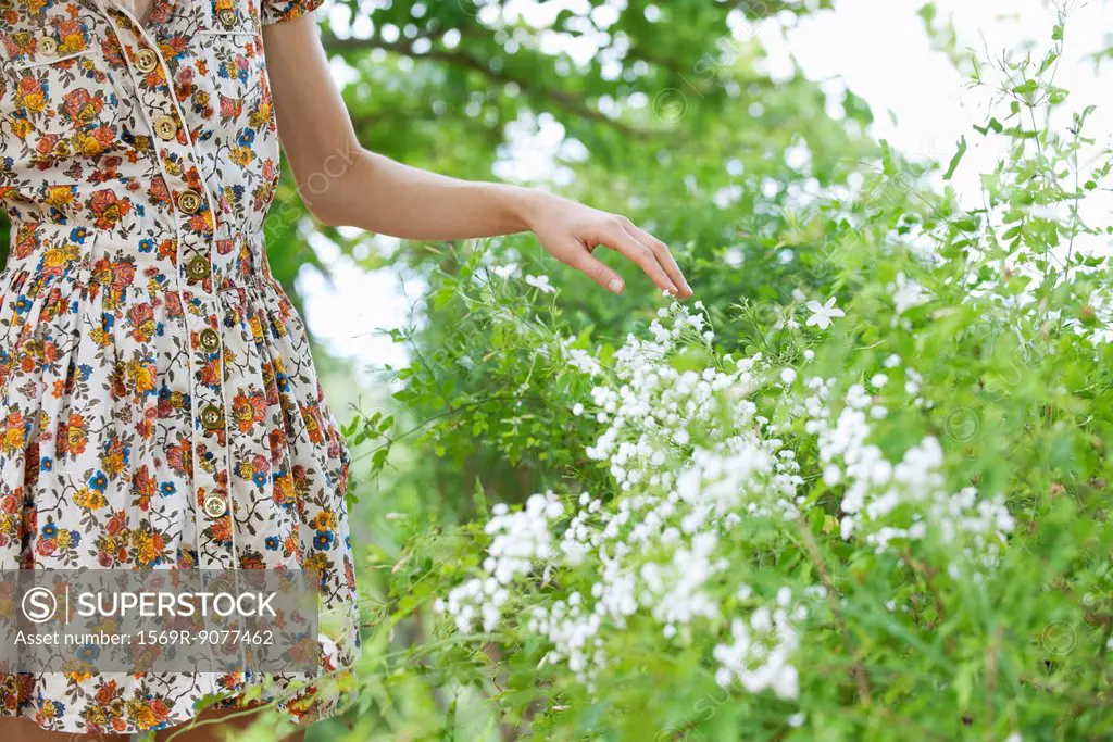 Woman touching wildflowers, mid section
