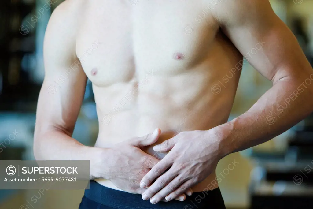 Barechested man with hands on stomach, mid section