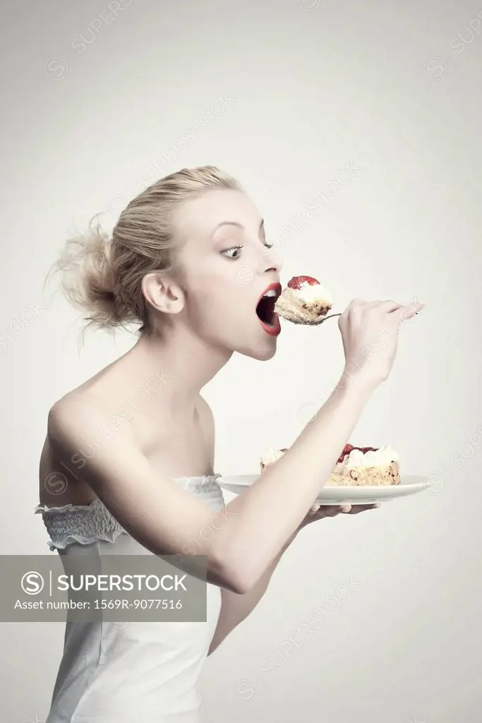 Young woman eating cake, side view, portrait