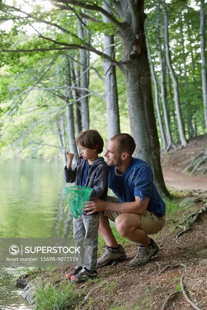Father and son fishing, boy staring at tiny fish in hand