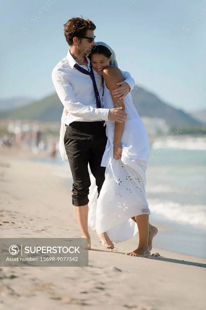 Bride and groom embracing at the beach