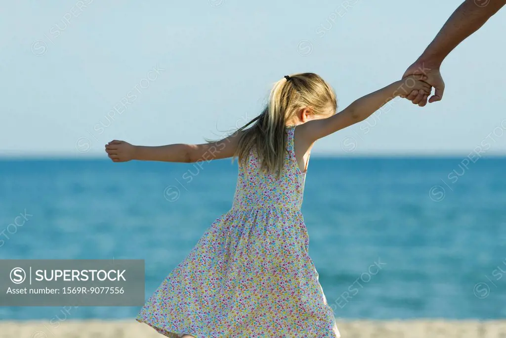 Girl walking at the beach, holding parent´s hand, cropped