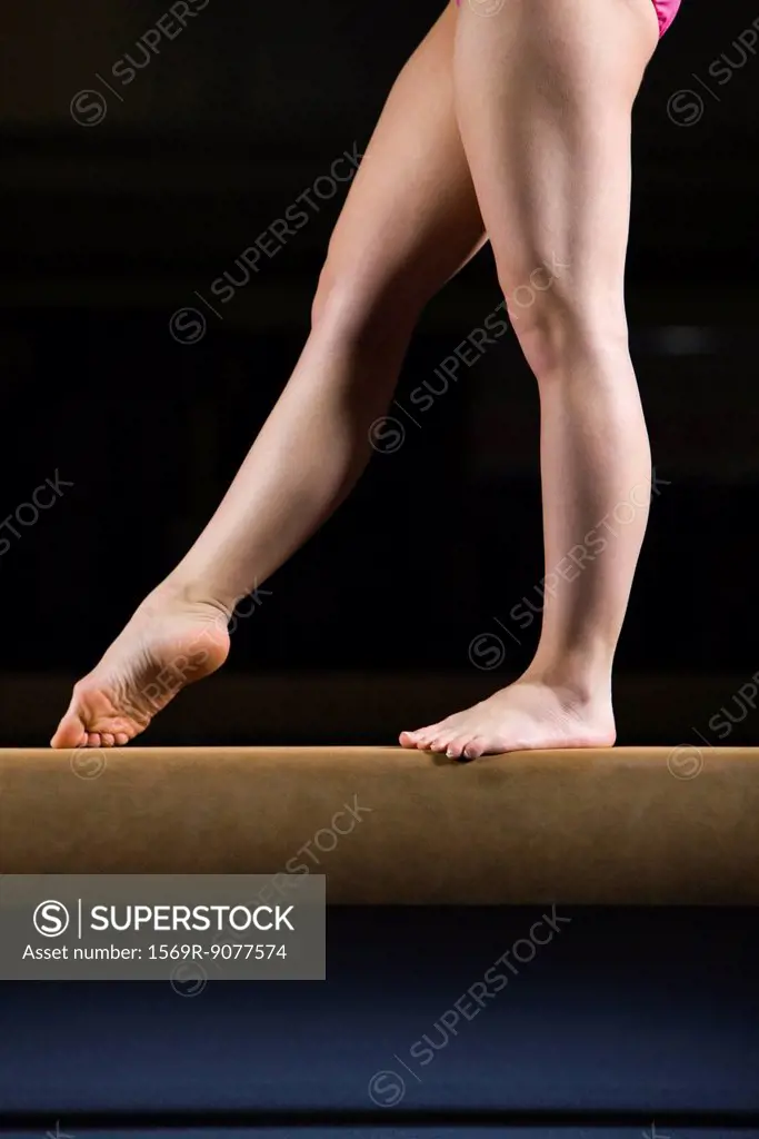Female gymnast on balance beam, low section