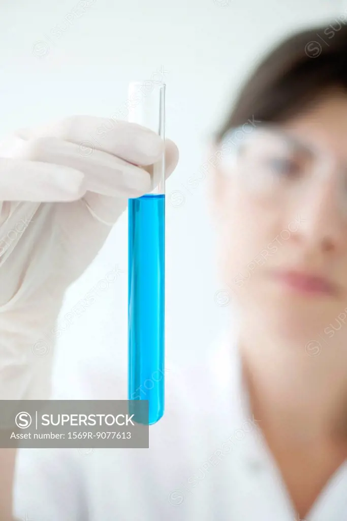Scientist holding test tube containing blue liquid