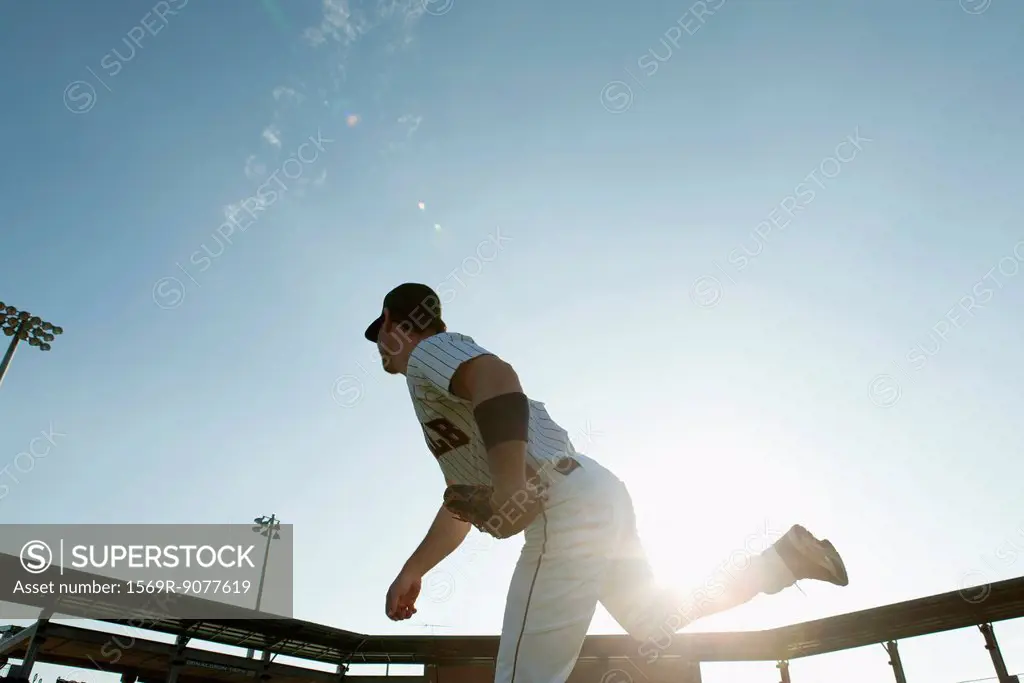 Baseball pitcher throwing pitch, backlit