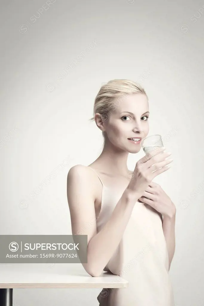 Young woman holding glass of water, portrait