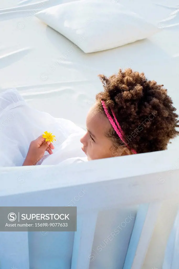 Little girl relaxing with flower in hand