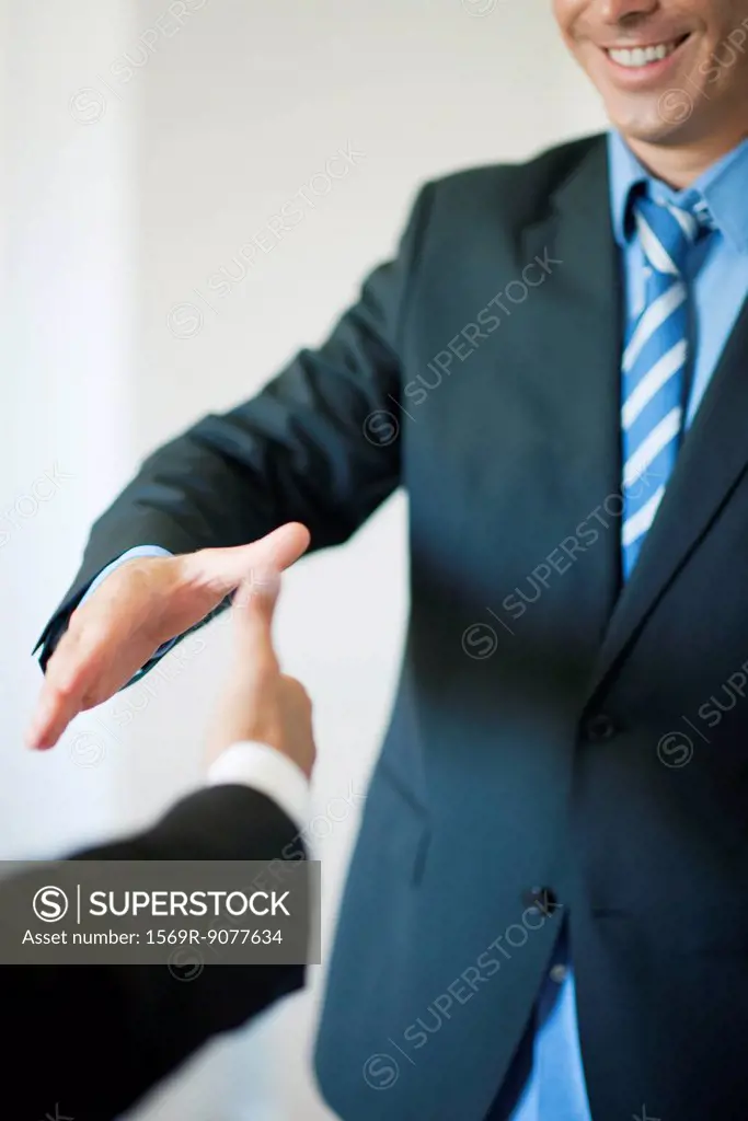 Executives extending hands to shake, cropped