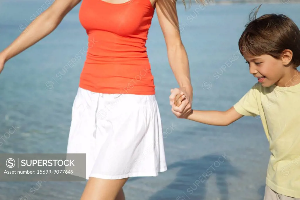 Boy holding his mother´s hand at the beach
