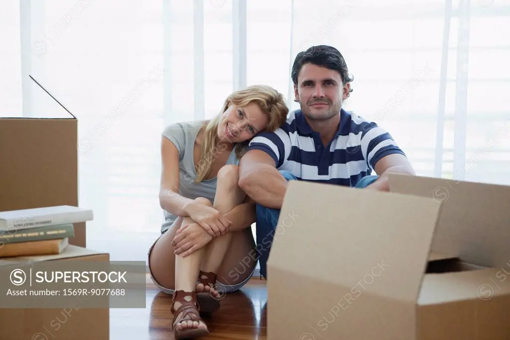 Couple sitting in living room with cardboard boxes
