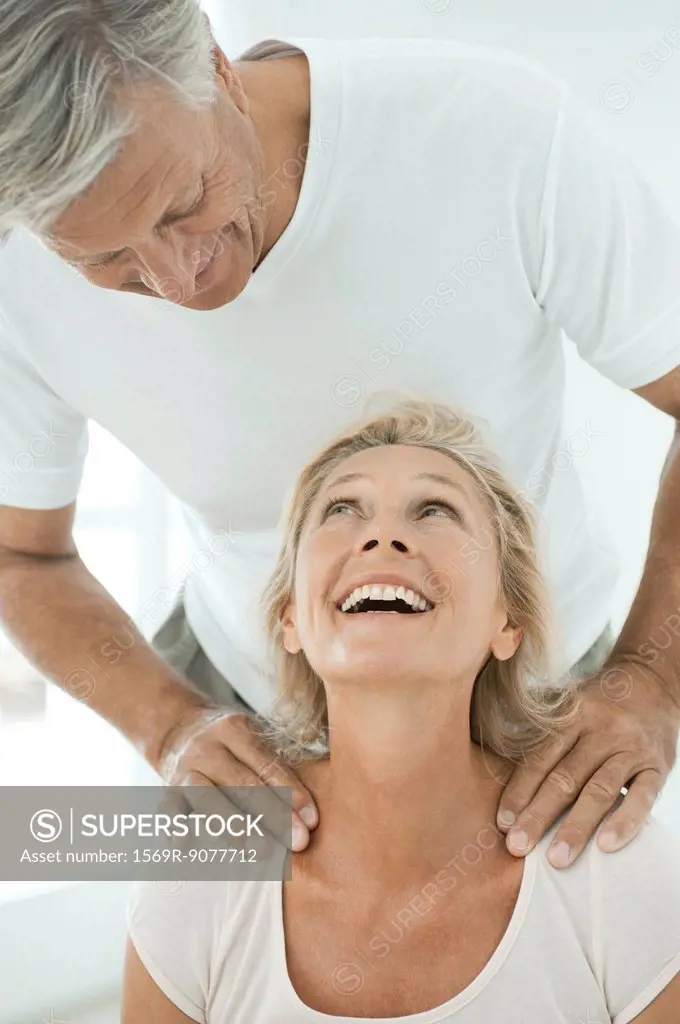 Mature couple smiling at each other as man massages woman´s shoulders