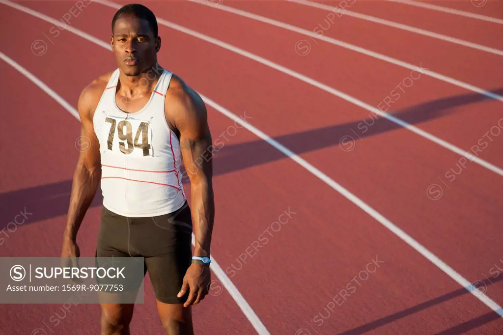 Young athlete standing on running track, portrait