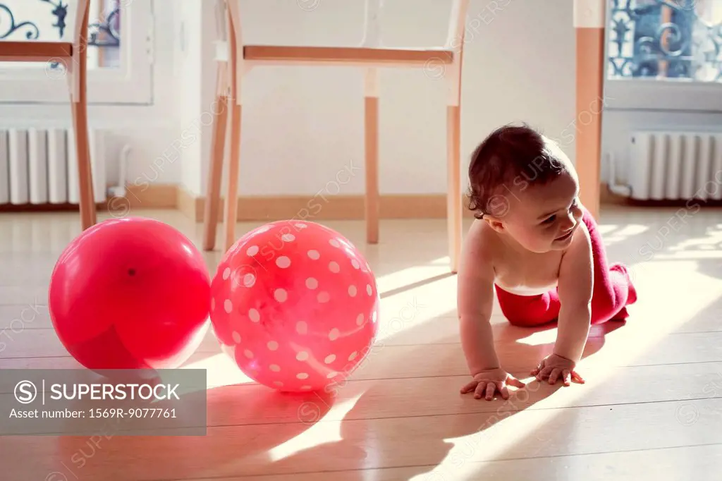Infant crawling by pink ballons