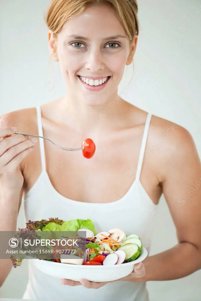 Young woman eating bowl of salad