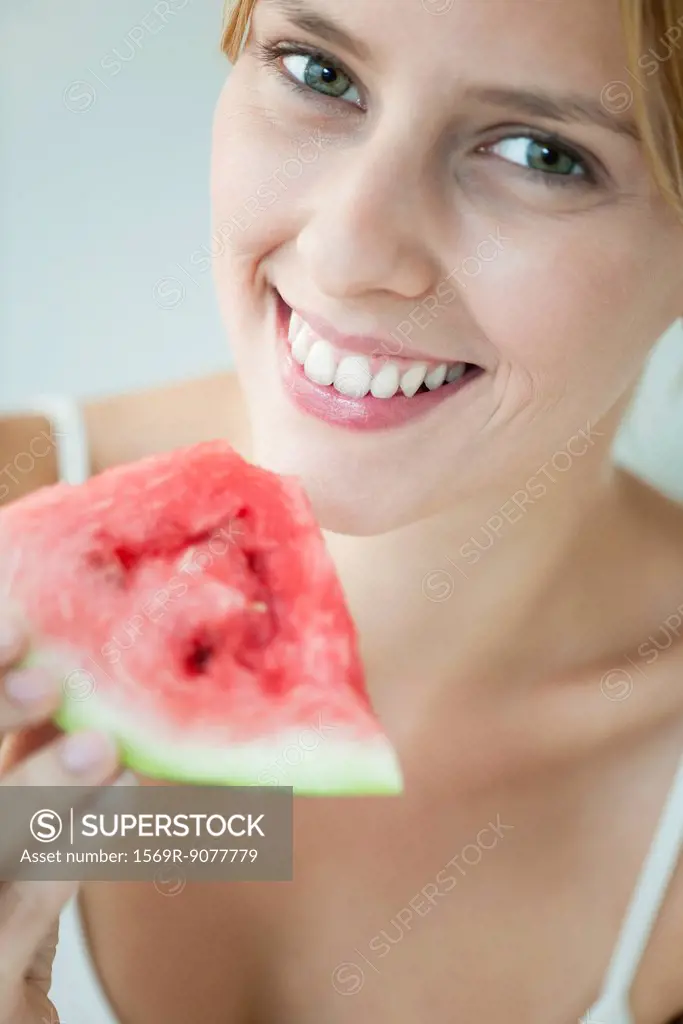 Young woman holding slice of watermelon, portrait
