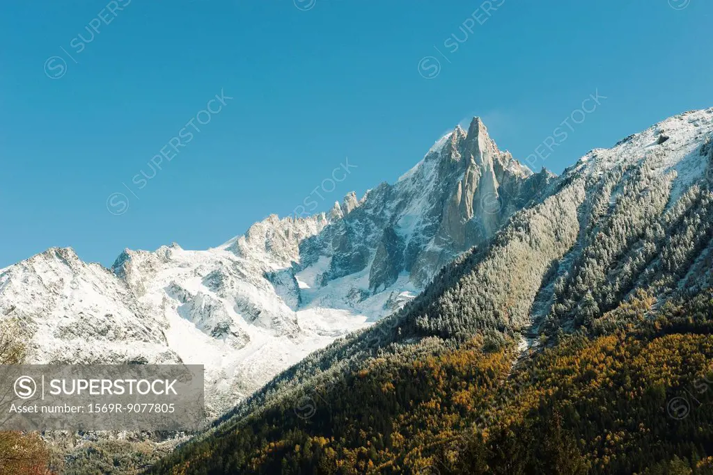 Snow_covered mountain range and forest in autumn hues