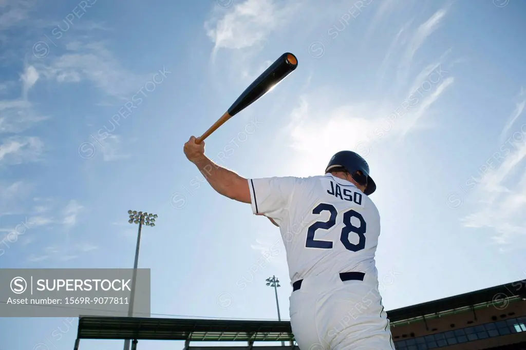 Baseball player swinging bat, rear view