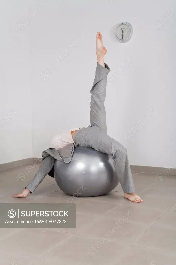 Businesswoman stretching on fitness ball in office