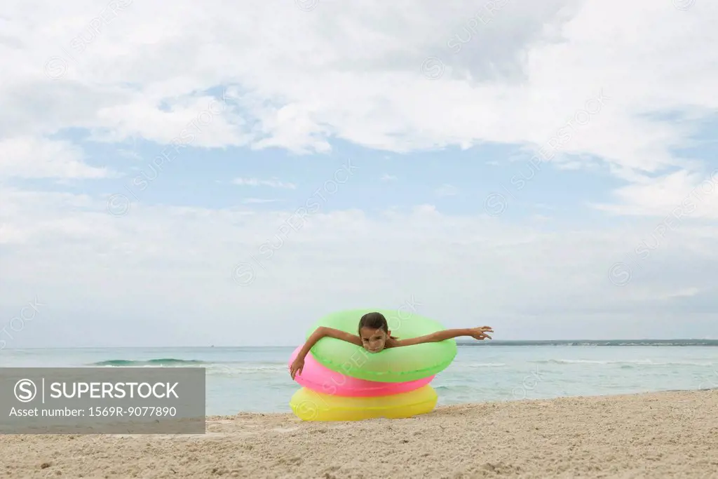 Girl playing with stack of infltable rings on beach