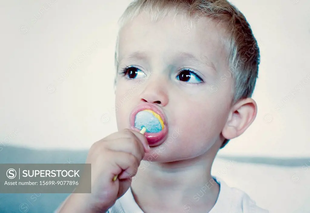Toddler boy eating lollipop, portrait