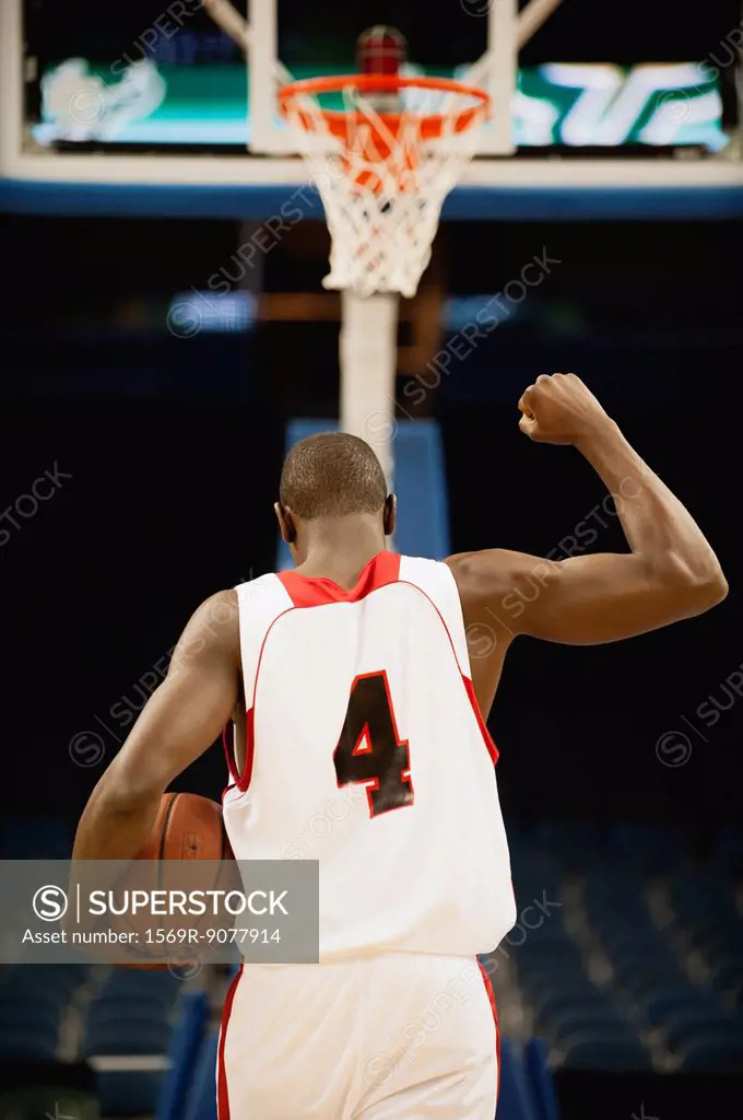 Basketball with fist raised in victory, rear view