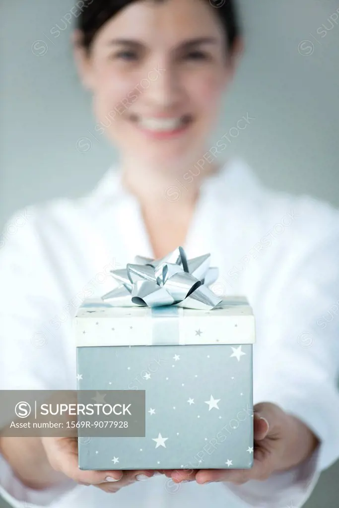 Woman holding gift box, focus on foreground