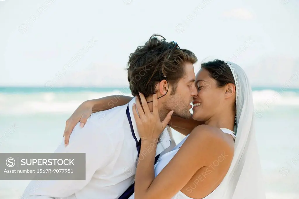 Bride and groom kissing at the beach