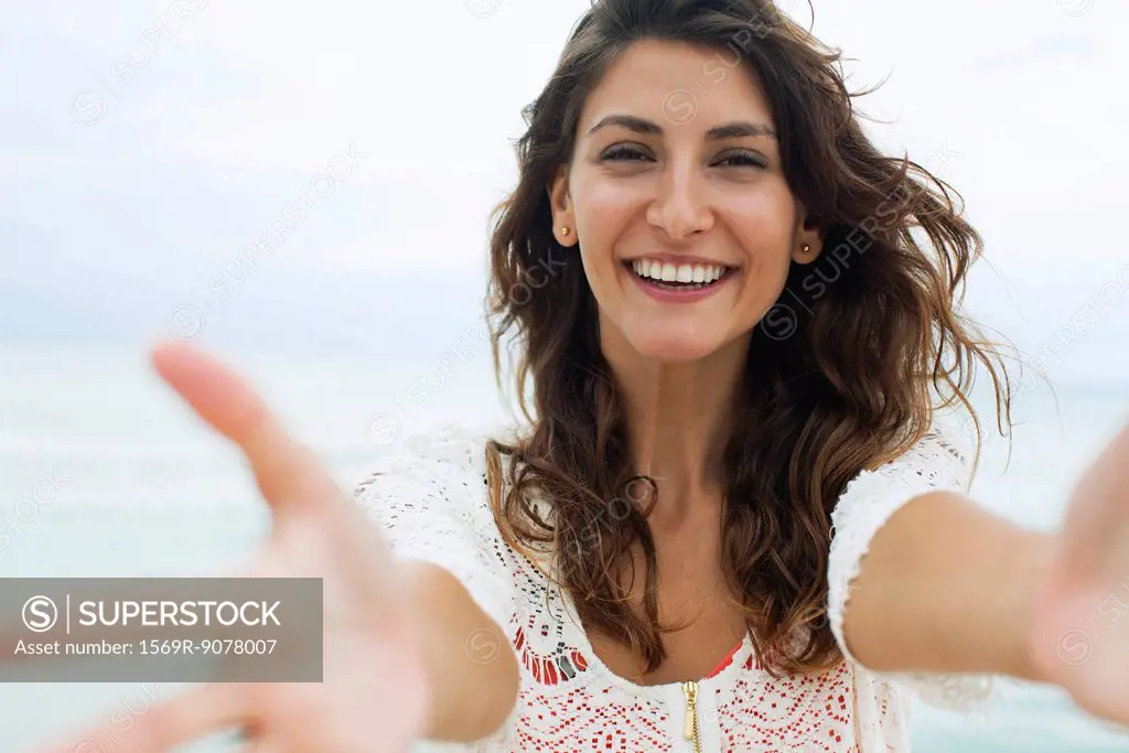 Woman reaching arms toward camera, smiling