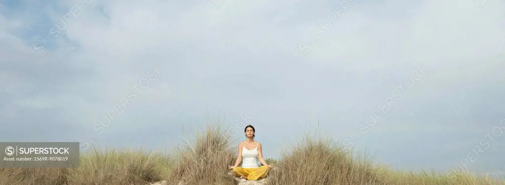 Mature woman meditating on beach