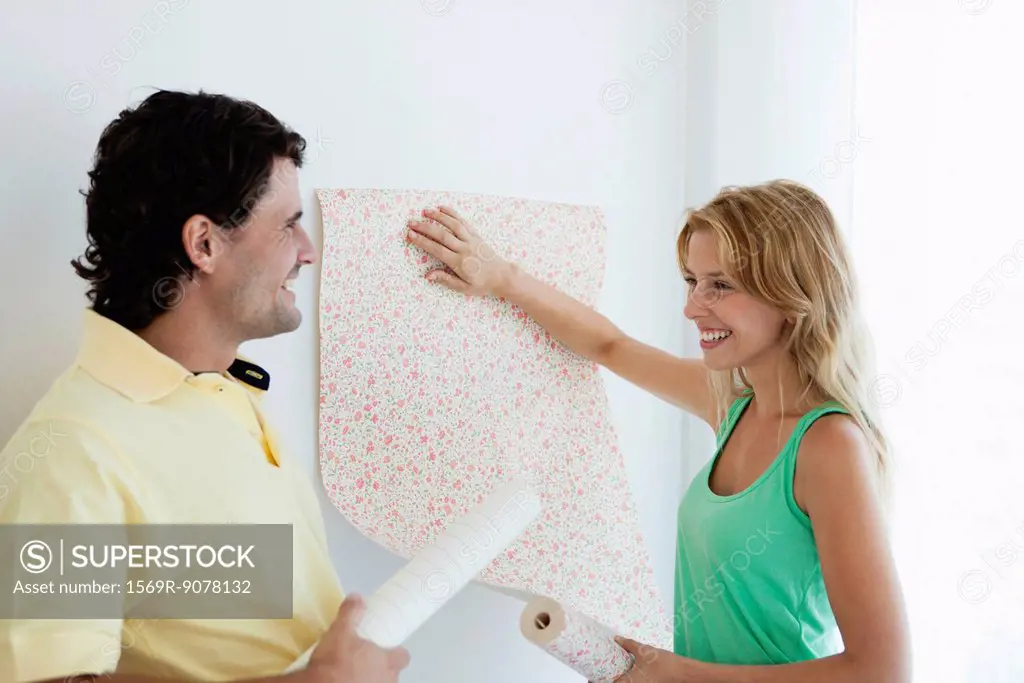 Couple decorating new house with wallpaper