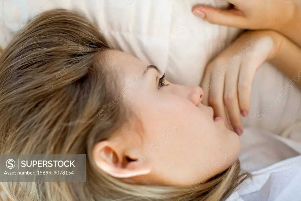 Woman lying down, looking away in thought