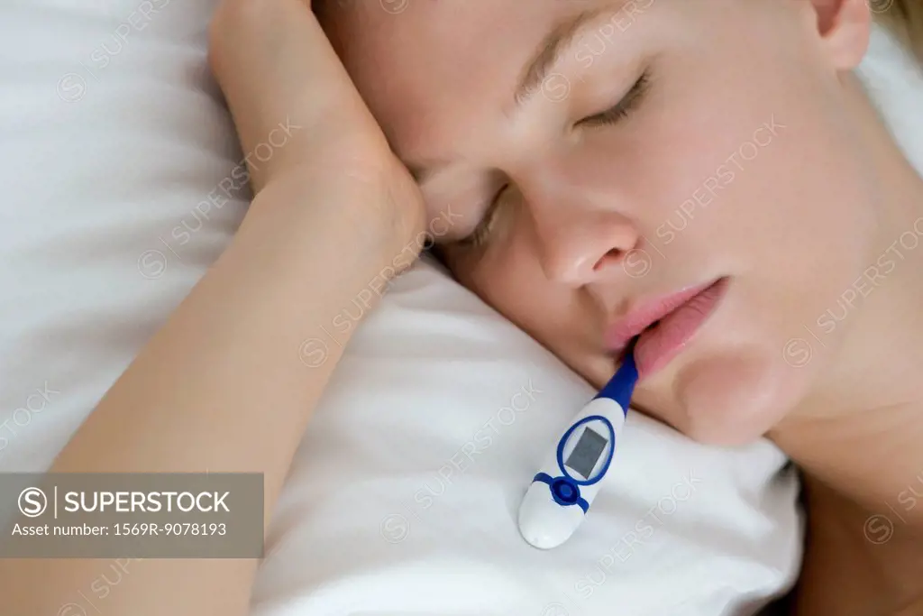 Young woman checking temperature with thermometer