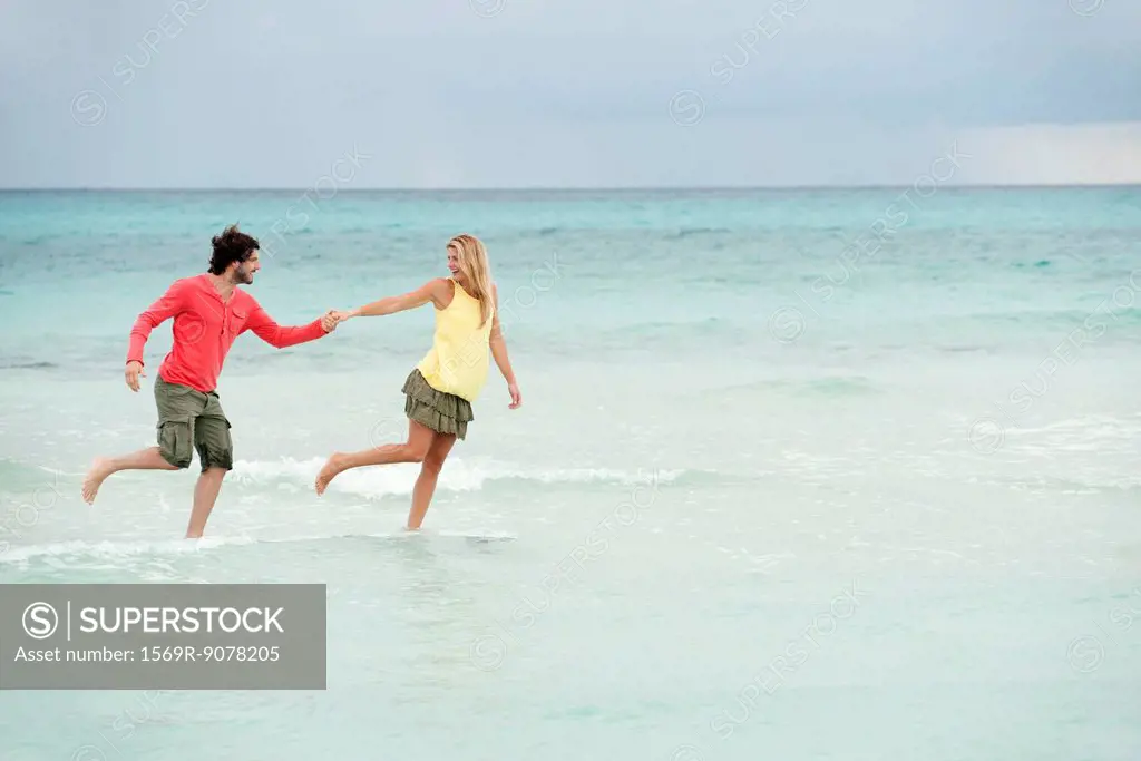 Couple running hand in hand in surf at the beach