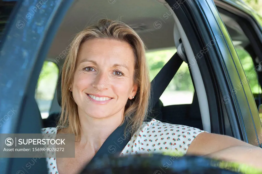 Woman in car, smiling out window, portrait