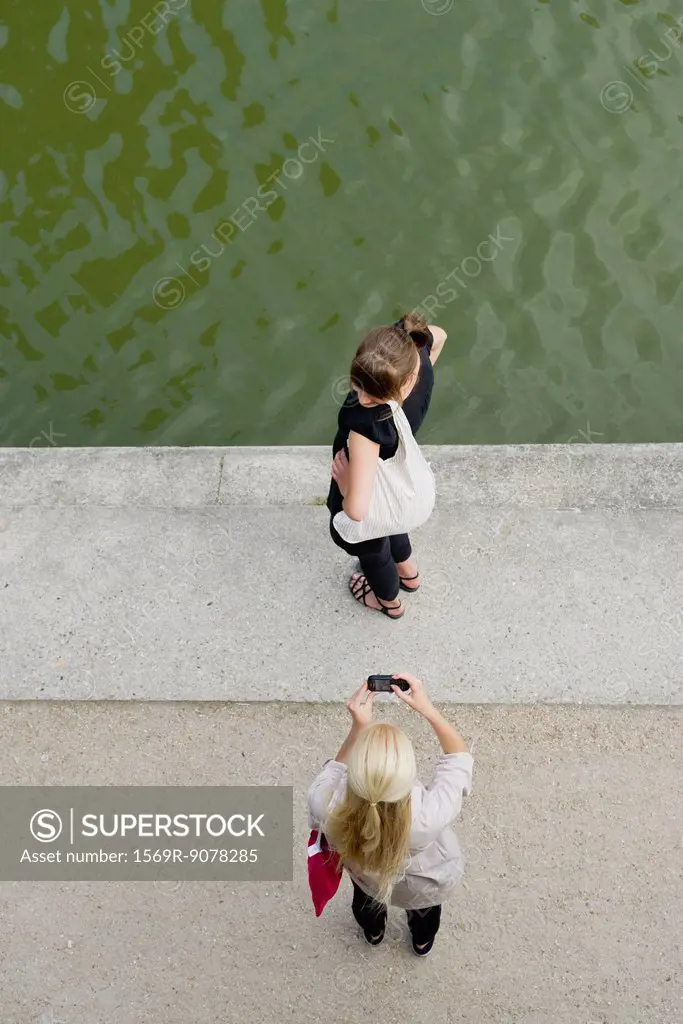 Young woman photographing friend with cell phone, elevated view