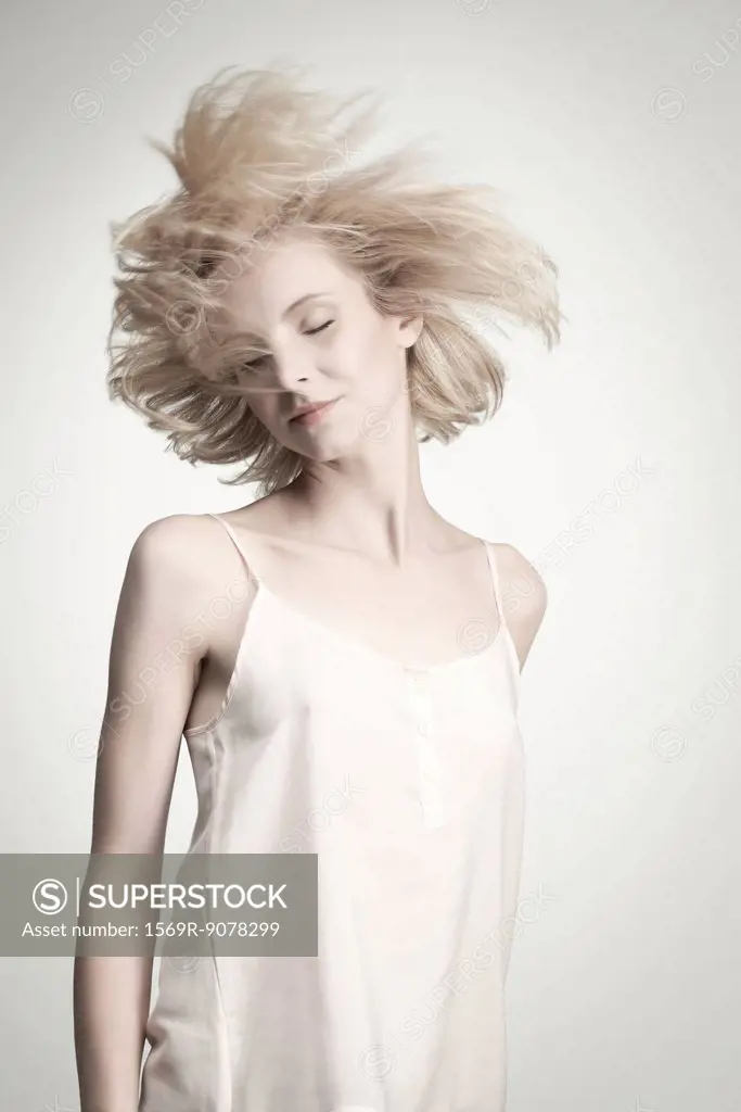 Young woman tossing hair with eyes closed