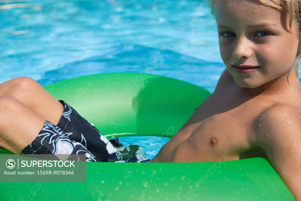 Boy relaxing on float in pool, portrait