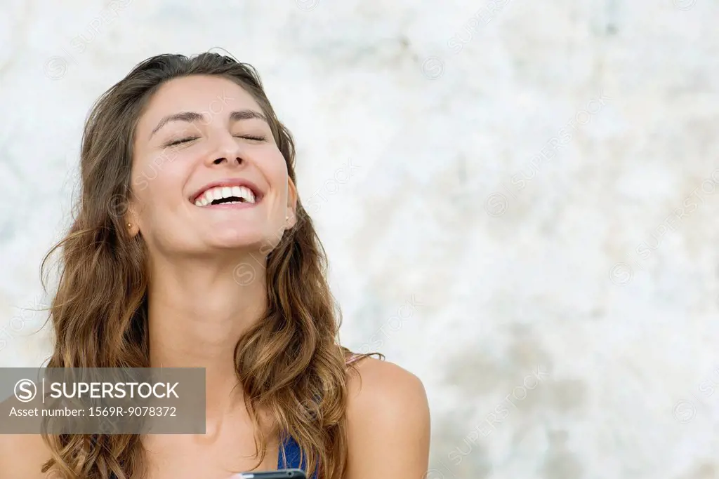 Young woman laughing, eyes closed
