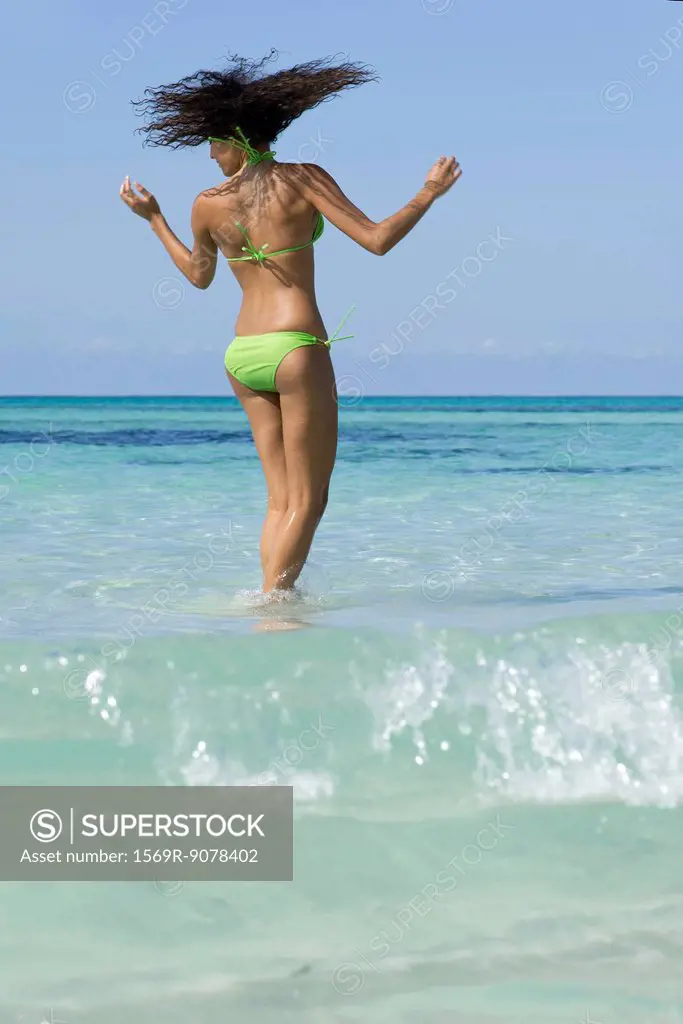 Woman in bikini standing in water, shaking head