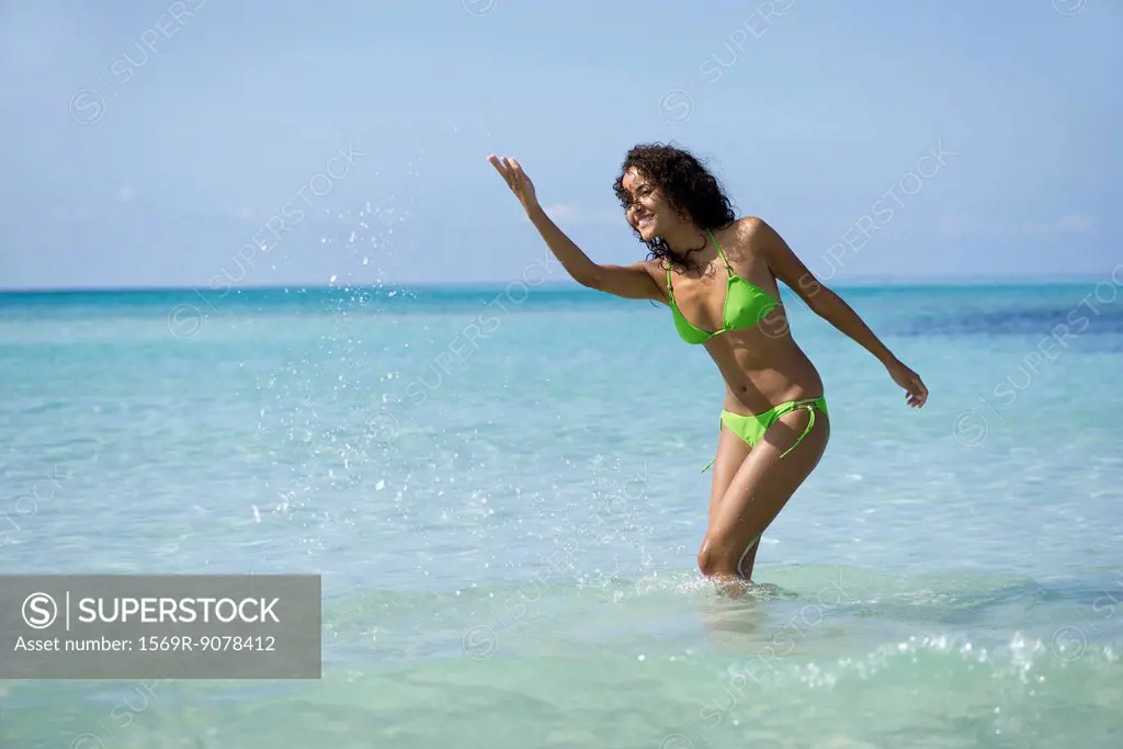 Young woman in bikini splashing water in ocean